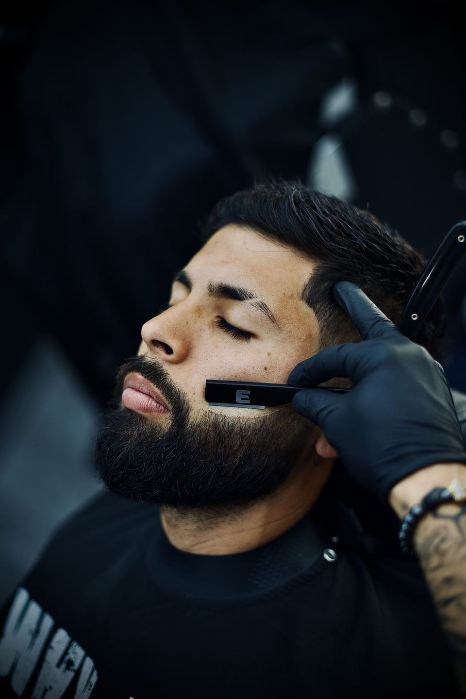 Barbero de Why Not Barbershop arreglando una barba con navaja