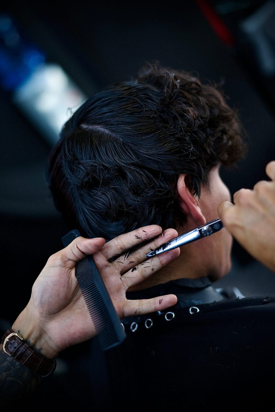Barbero de Why Not Barbershop realizando un corte de precisión con tijera